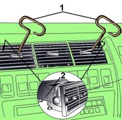 Использование приспособления из проволоки (1), установленного в отверстия (2) для снятия вентиляционной решетки из центральной секции панели приборов